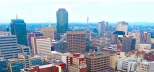 Over a lifetime, the Harare skyline has changed beyond recognition. With notable exceptions – the High Court, the foreign ministry, the Munhumatapa building ( time on the clock tower has long been stopped at twenty past three) - most of the squat colonial buildings are gone, giving way to gleaming towers of steel and glass. An old man on his first trip from deep in the rural areas marvelled at the new buildings and remarked that us the townspeople appeared to be obsessed with glass. “You even cover your eyes with it,’’ he said to a bespectacled me. He wasn’t impressed at all by the Karigamombe Centre or the faded gold façade of the Rainbow Towers – “Golden Delicious” as it was known to taxi drivers before the elements of sun and storm took their toll on the then Sheraton. Nor was he impressed by the imposing edifice of the central bank. On the bus on the main road from the west he could see the Reserve Bank from some 20 kilometers away. It is designed to be seen from all the city’s main approach roads. He didn’t know until I told him that the bank’s octagonal design is symbolic of an upended maize cob - maize being the once abundant staple food and the cob-like skyscraper represents the Horn of Plenty, the nation’s cornucopia. Inside, it has marble trimmings and suites and boardrooms to match the best in Frankfurt or London. Alas, as the economy took strain in recent times, the Horn of Plenty emptied soon emptied. A few blocks away, across my home town, is Eastgate, a fine shopping mall and office complex behind Meikles hotel that has rows of rooftop chimneys. When the building is lit after dusk it looks like an old steamship ploughing into the night. It was Zimbabwe’s first really “green” construction project, based on nature’s self-ventilating anthill. Its designers insisted it saved 70 percent of the energy costs the central bank building would gobble up. Walking on chill winter mornings in the multiple green belts and vleis of Harare, I have often watched condensation stesteaming from the conical anthills as the worker ants aerated the depths of their nest. Beautiful Harare is much like other former British colonial capitals whose planners allowed for plenty of tree-lined avenues and open spaces, quite unlike the cities in former French or Portuguese territories. Late in the year, we are washed with the magnificent lavender blossoms of the prolific jacaranda tree. The main square, Africa Unity Square, has been a sight to behold for as long as I can remember at jacaranda time. The flower sellers and curio stalls add their colour to the square but the central fountains don’t seem to perform their kaleidoscopic water dance anymore. I wondered in the 1970s why they pulled down the fine old fashioned Meikles hotel, but it was progress, we were told. The old Meikles had a Palm Court orchestra in the ballroomplaying jazz standards and tea-room waltzes. The square on Meikles’ north side was where the colonial era settlers raised the Union flag right opposite The Herald offices of today. They hadn’t intended to set Fort Salibury here, but it was unclear where a better site for the catchment of natural water was to be found. By the time it was, it was too late to move the settlement. So Harare is actually in the wrong place. An underground water course runs along Seke Road and Julius Nyerere Way up to Harare Gardens and the Avenues district of apartments and townhouses. When I lived in the Avenues, my uncle, a water diviner, believed one reason I slept uneasily could be that my bed was placed east-to-west, against the flow of the water beneath. I was in its negative field. I moved the bed north-to-south. It worked. But it might have been a psychological thing, I suppose. Back then, the dormitory township of Chitungwiza was mushrooming 25 kilometres to the south of the city centre and it was proposed by various armchair engineers that the underground river could be excavated and made into a canal for commuter barges. We could become the Venice of Africa…The idea, of course, never got beyond the armchairs. In any city, there is always a dividing line between the ritzy executive offices and the hugger mugger of real life. Ours is Julius Nyerere Way. Cross it going west and enter a bustling tumult of wholesalers, shoe shops, stores for cheap clothing, haberdashery and aromatic spices, cafés, take-aways and liquor marts blaring loud Afro-pop over the pavement. And beyond that, of course, there are the “high density” suburbs, once the segregated townships where colonial planners put the workers needed for Harare’s factories and businesses. Harare’s political nationalism has its mother lode in Highfield township where as young reporters many, many moons ago, we enjoyed the bars, shebeens and hotels – notably the Mushandire Pamwe hotel _ and listened to real township music at the Saratoga nightclub. My own “low density” suburb of Eastlea awakens with the surround-sound of the dawn chorus that no iPod could ever match. An artist friend of mine advises the best way to start the day is to listen to the birds for five minutes before switching on news programmes or beginning other stressful activities. The dawn chorus today may be accompanied by the rumble of petrol generators. I regard Harare, even though it’s worn, littered and horrifically potholed right now as my town and I love it. I and journalist colleagues of my vintage knew almost all the nationalists after whom streets were renamed after independence. In my travels over the years, I met Jason Moyo and Herbert Chitepo, both later to be murdered, and after 1980 I lived in a flat on Herbert Chitepo Avenue. I had met Josiah Tongogara, I had befriended George “TG” Silundika, I knew Josiah Chinamano and I had spoken with or interviewed Nelson Mandela, Julius Nyerere, Kenneth Kaunda, Samora Machel, Sam Nujoma and – it should go without saying - President Mugabe. The museum at Heroes Acre displays the old VW beetle in which a bomb killed Herbert Chitepo. We as reporters had dealings with almost all the fallen who lie at Heroes Acre. What’s more, if you have lived as a journalist in a city as long as I have there’s hardly a block of flats or an office building I haven’t been inside at some time or another, nor a bar, school, hospital, church, courthouse or even jail. You can’t say that about many capital cities of the world. That’s where my father’s remains rest, there are the offices where the corporate vipers lied to us, that’s where my pension evaporated in hyperinflation, that’s where we held the wake for dear but tormented Frank Moore, a school friend, after his suicide 35 years ago. That’s the cemetery where Frank’s bones sleep, that’s where Catherine lived … reminding me whenever I pass it of John Le Carre’s words: there were some women who carried their bodies as if they were citadels to be stormed by only the bravest. Maybe it’s a small town thing. Indeed, we are comparatively small and my Harare roots may well be comparatively shallow. But my dictionary defines: Roots, pl, n, the close ties one has with some place or people as through birth, upbringing, long association etc. I don’t care what anyone says. Harare, my birthplace, is home and, God willing, I’m not going anywhere else.